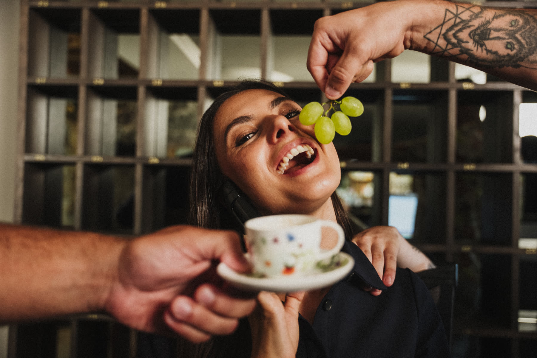 Betti laughs at the front desk while her team hands her coffee and grapes